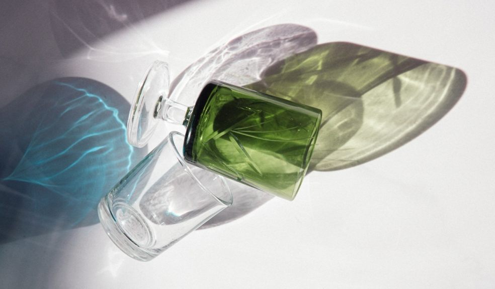 transparent and green glass bottles lying on top of a white table